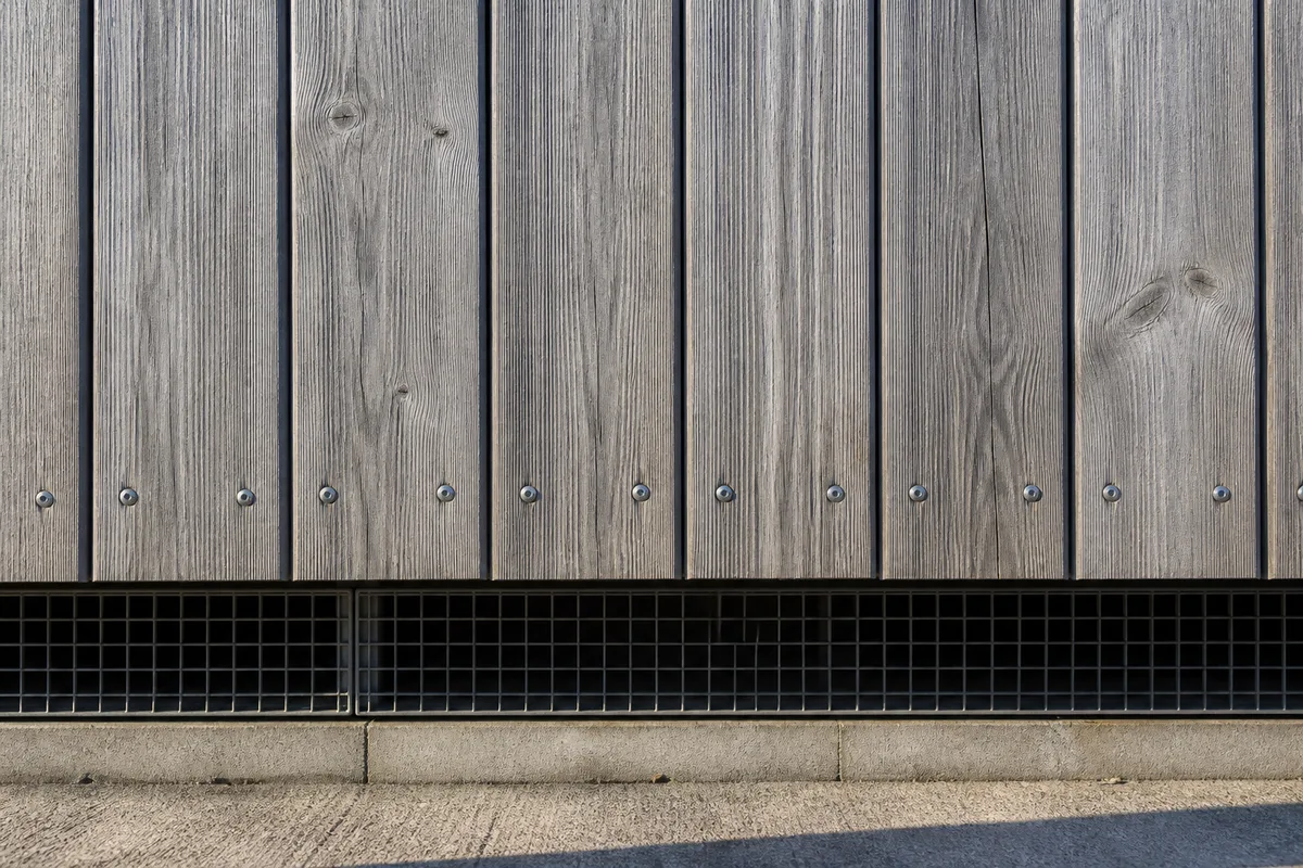 Bardage bois vertical ventilé sur une façade côtière, fixations métalliques apparentes